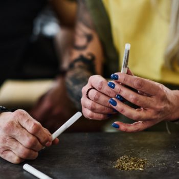 Couple Rolling Handmade Cigarettes At Table